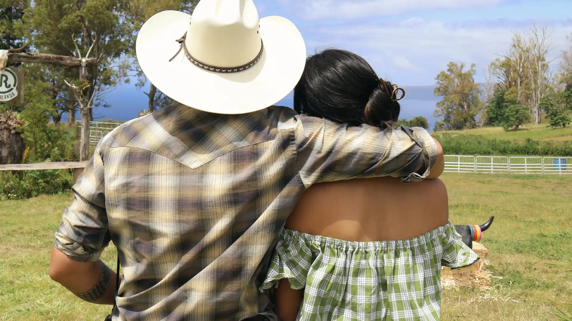 Couple in cowboy hats embracing on the ranch lawn
