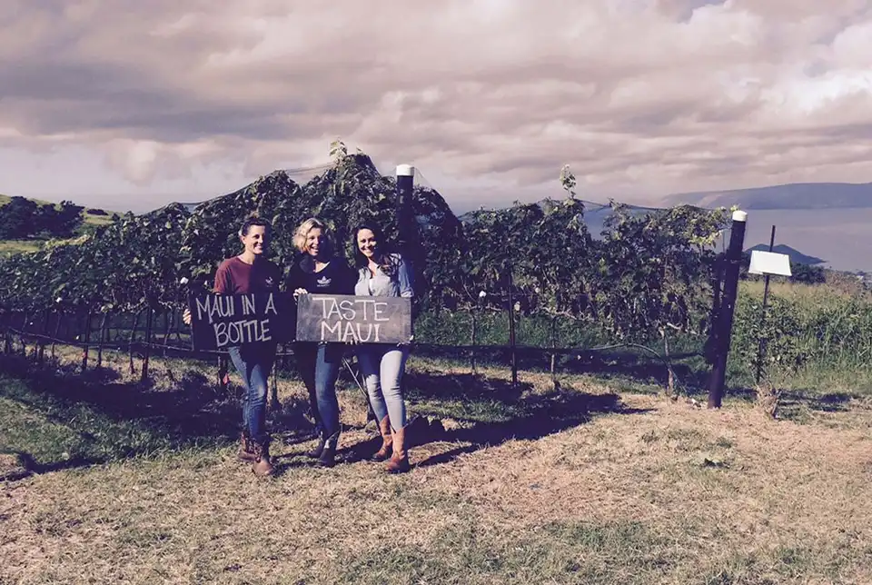 Historic photo of three people holding a sign in the vineyard