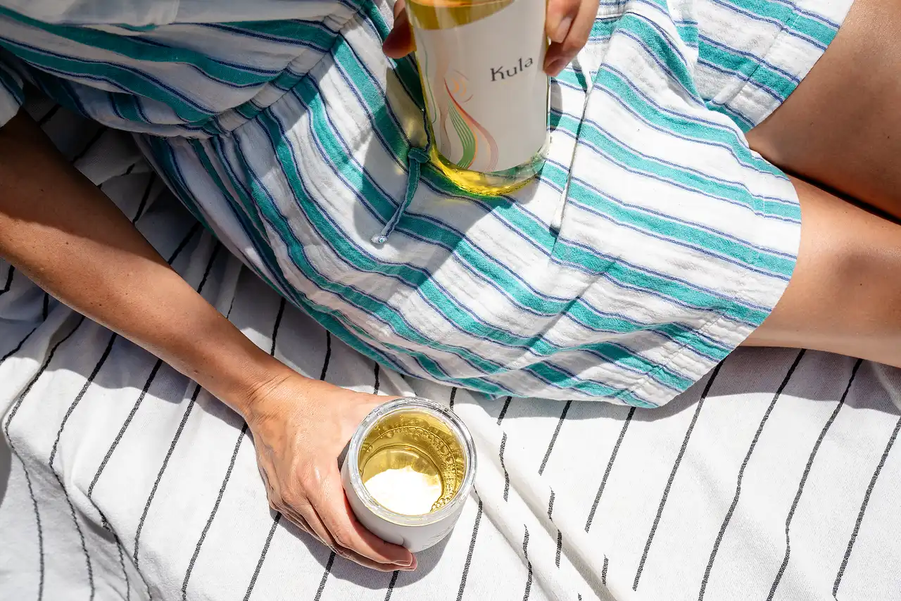 Relaxing with a glass of Kula white wine on a striped lounge chair