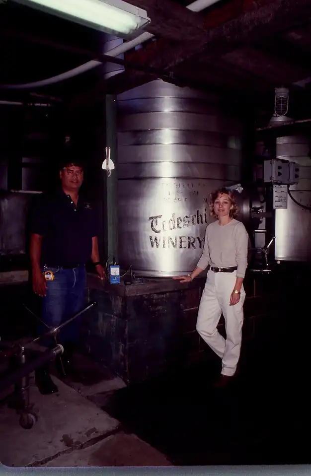 Historic photo of two winemakers beside a stainless steel tank