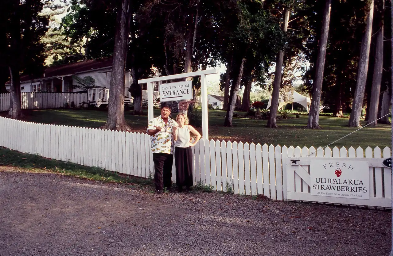 Historic photo of a couple at the Tedeschi Winery sign and white picket fence