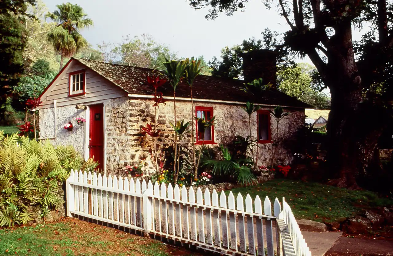 Historic photo of the King's Cottage stone building with a white picket fence