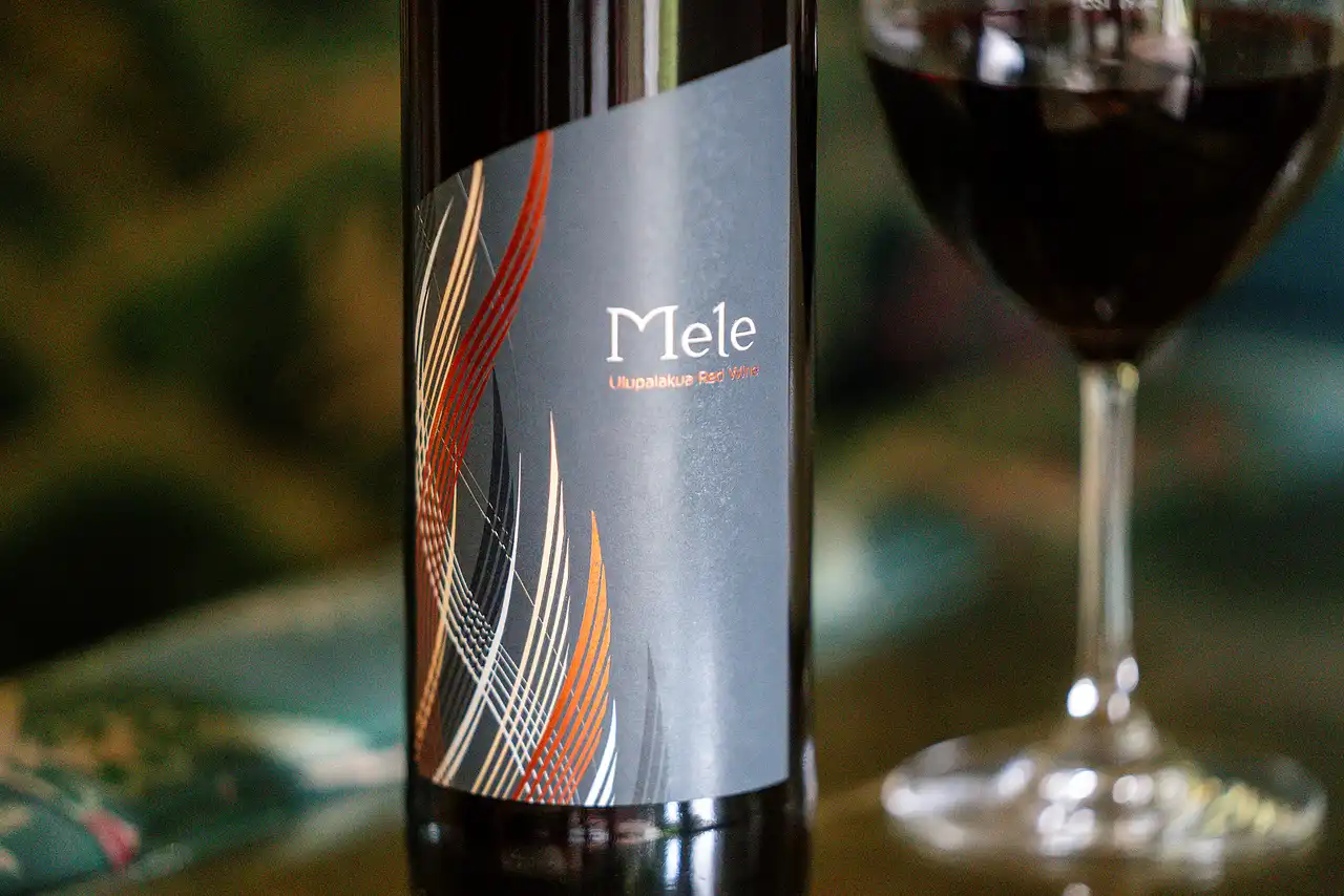 Bottle of Mele red blend beside a glass of red wine