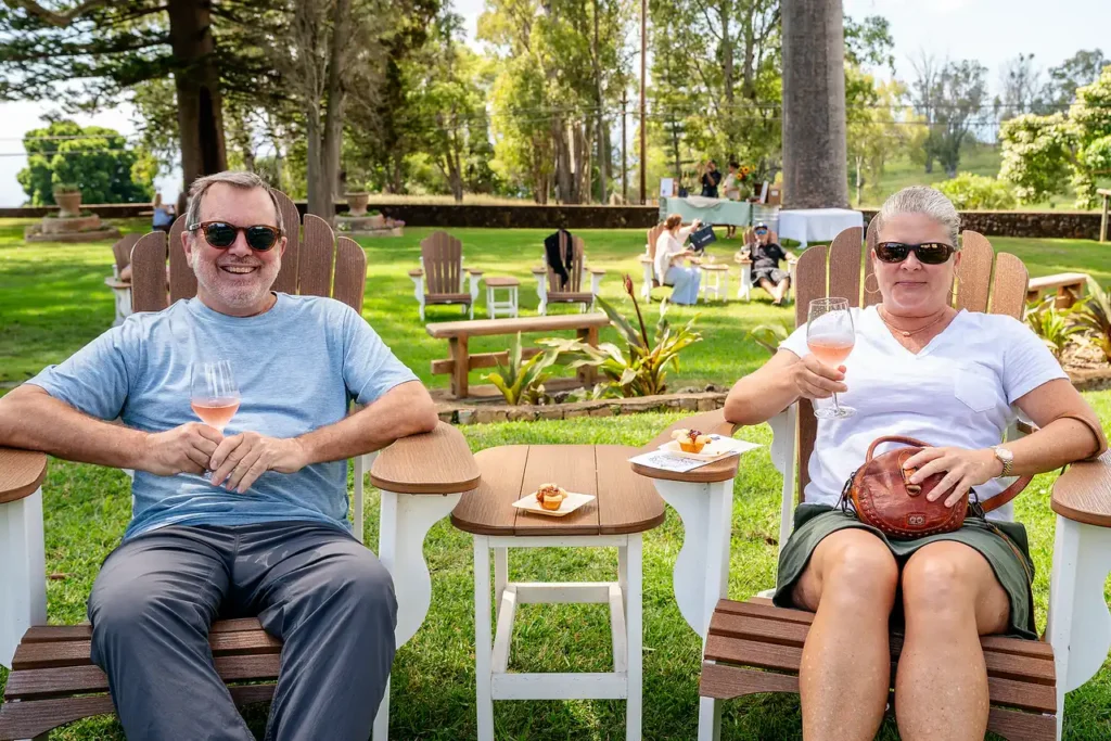 Couple relaxing in Adirondack chairs with wine on the estate lawn