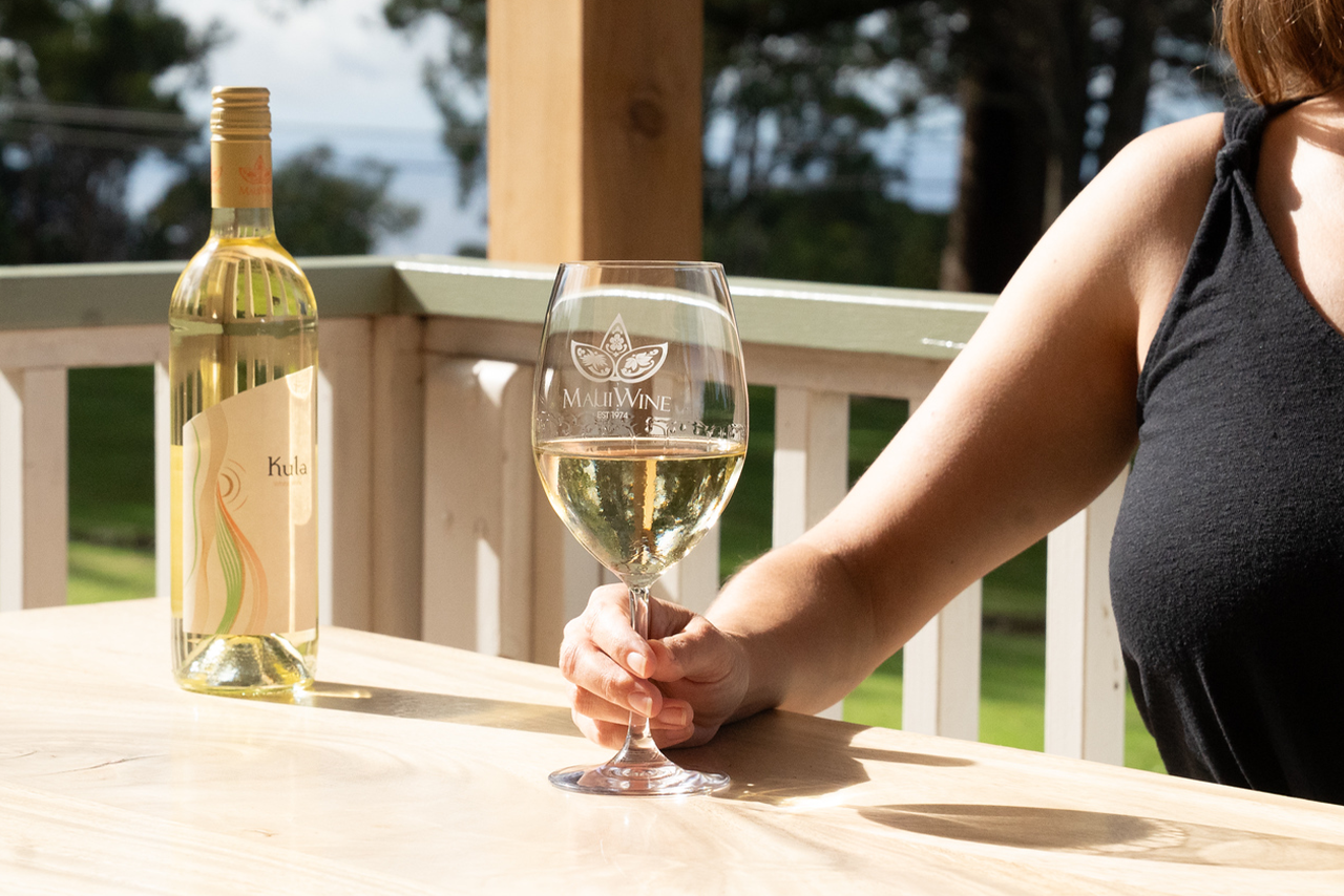 Guest holding a glass of white wine on the tasting room porch