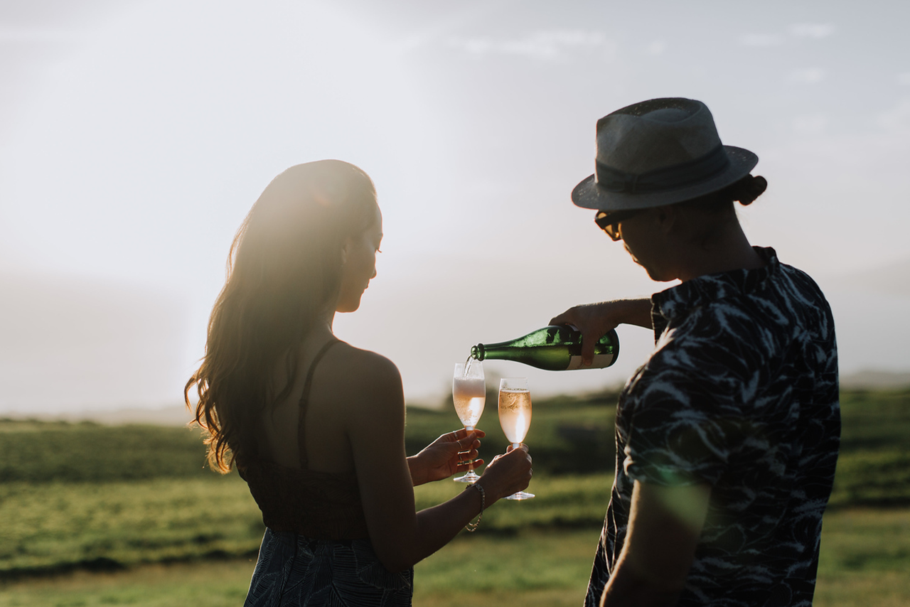 Couple pouring wine outdoors at sunset in Upcountry Maui