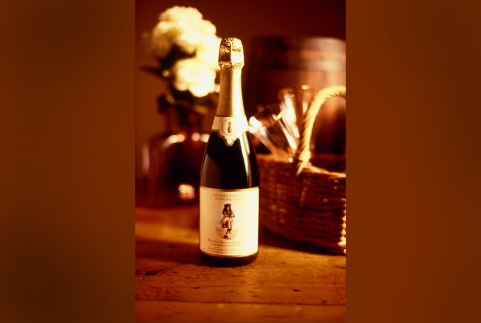 Bottle of MauiWine sparkling wine beside a wooden crate